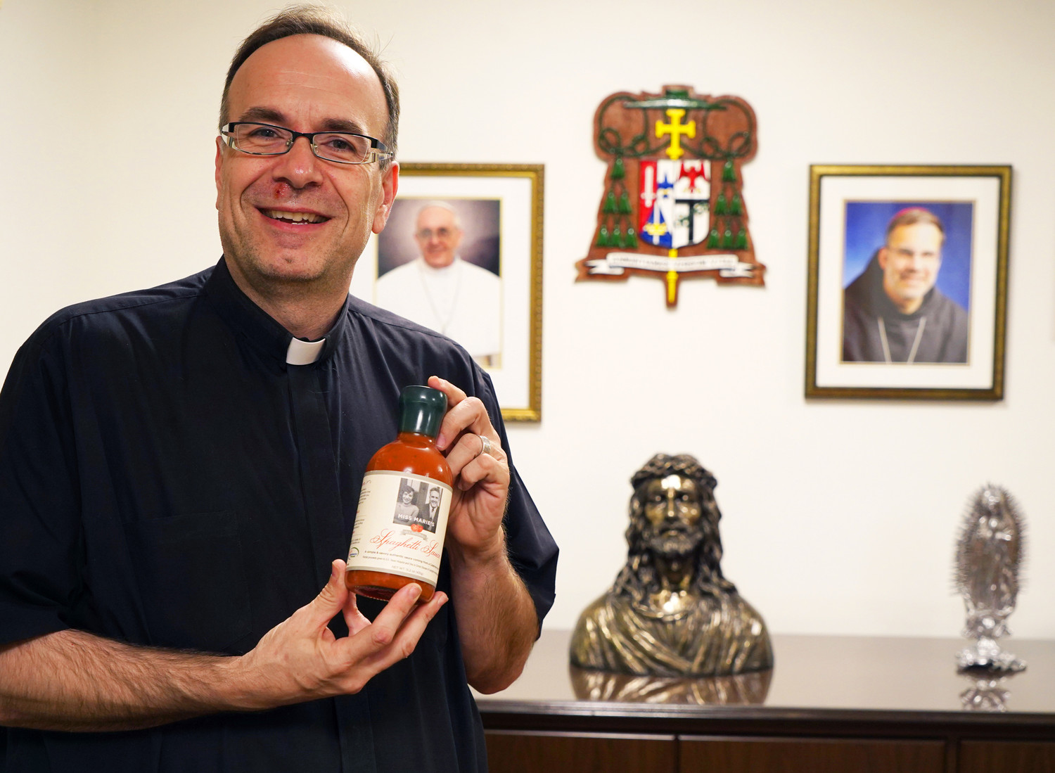 Father Jim Sichko poses with a bottle of Miss Marie’s Spaghetti Sauce at the offices of the Diocese of Lexington, Ky., on Oct. 26. Father Jim used his mother’s tomato sauce recipe to create the product and is donating part of the proceeds of sauce sales to the Lexington Diocese and Southeast Texas Hospice.